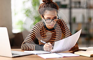 Focused smart young african american woman working online on laptop or female student studying online at home