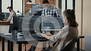 Focused software developer writing code looking at multiple computer screens