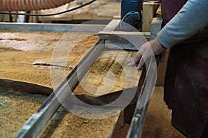 Focused and steady, an artisan slices through wood with a bandsaw. This tool is essential for his meticulous craft.