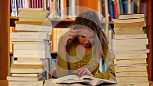 Focused student studying in the library surrounded by books