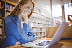Focused student using laptop in library