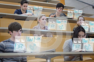 Focused students in lecture hall working on their futuristic tab