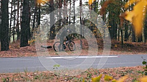 Focused stylish young professional cyclist in black cycling apparel, helmet and sports glasses starts riding on road bike in fall