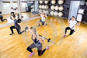 Focused team doing split squats with weights at fitness gym