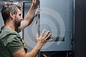 Data center technician installing a server module in a network rack during hardware maintenance