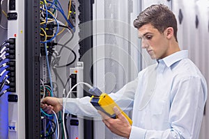 Focused technician using digital cable analyser on servers