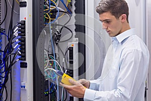 Focused technician using digital cable analyser on servers