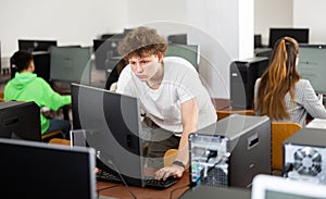 Focused teenager studying with classmates in computer lab