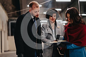 A focused trio of professionals collaborates on project notes in an office building hallway with a sleek, contemporary