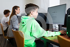 Focused tween boy studying with classmates in computer lab