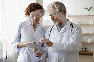 Focused two different generations doctors using computer tablet.