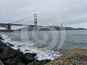 Focused View of a concrete block and a Tree trunk with a blurry background of Golden Gate Bridge