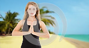 Focused white woman doing namaste mudra gesture in front of summer sea