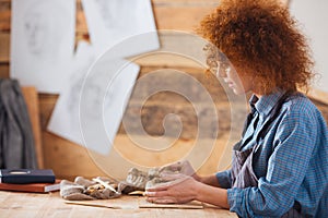 Focused woman ceramist creating sculpture using clay in pottery workshop