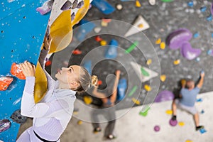 Focused woman climbing without ropes and harnesses on artificial bouldering wall