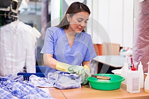 Focused woman drycleaner removing spots and stains