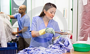 Focused woman drycleaner removing spots and stains