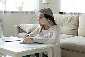 Focused woman in headphones watch webinar on laptop writing notes