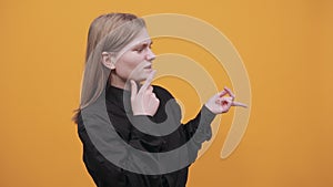 Focused woman keeping hand on chin, pointing finger aside, thinking about issue
