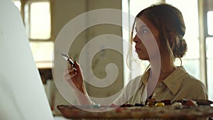 Focused woman painting on canvas. Creative female artist working in art studio.