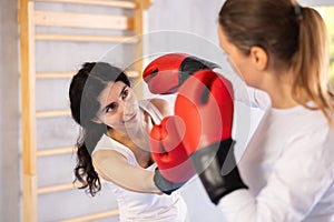 Focused woman practicing boxing punches in sparring during group self defence course