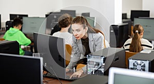 Focused woman sitting at table in computer room in public library