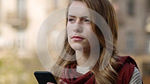 Focused woman waiting email on phone outdoors. Closeup girl touching cellphone