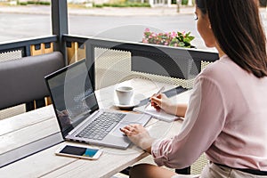 Focused at work. attractive young businesswoman, freelancer or student in casual clothes working on laptop and making notes in her