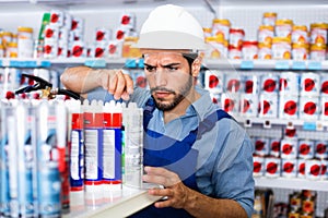 Focused workman choosing materials for renovation works in paint store