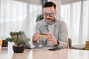 Focused young adult man, holding credit card, inspecting it