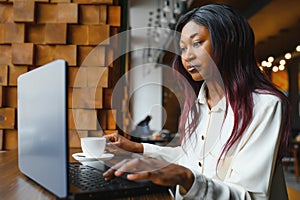 Focused young african american businesswoman or student looking at laptop, serious black woman working or studying with computer