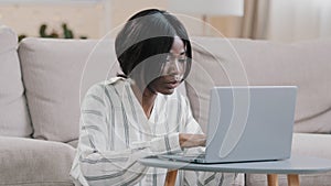 Focused young african american woman freelancer typing on laptop working remote at home girl distance learning using