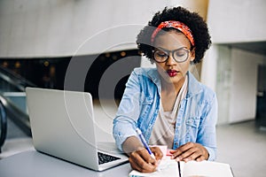 Focused young African female entrepreneur writing down business photo