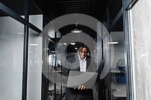 Focused young black businessman working online on laptop in office. Remote work