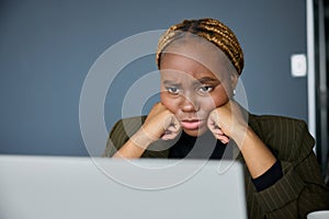 Focused young black businesswoman in businesswear working on laptop in office