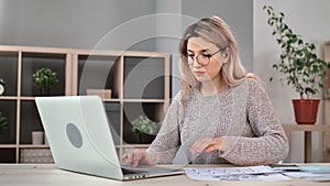 Focused young blonde business woman chatting surfing internet on laptop pc medium tracking shot