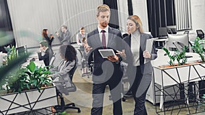 Focused young business colleagues looking at digital tablet and discussing project