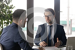 Focused young businessman in formal wear talking with partner.