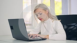 Focused young caucasian woman college university student doing homework assignment using laptop computer typing studying