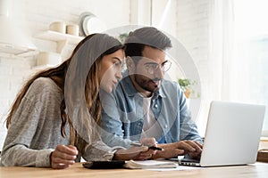 Focused young couple calculating bills, planning budget together