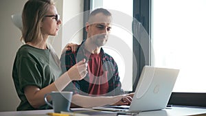 Focused young couple wife and husband looking at the laptop screen indoors