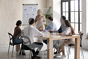 Focused young diverse employees listening to older 60s team leader.