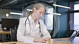 Focused young doctor doing paperwork in modern office