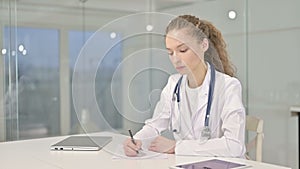 Focused Young Doctor doing Paperwork in Modern Office