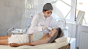 Focused young female cosmetologist performing facial skin cleansing with ultrasonic shovel on woman to enhance efficacy