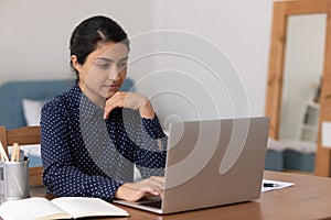 Focused young indian woman analyse data on computer screen