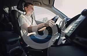 Focused young man driving car confident. Teenager driver respecting the traffic rules on the ride, keeps hands on the steering