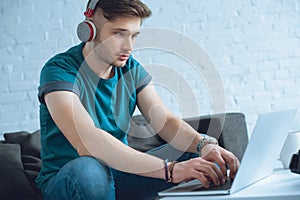 focused young man in headphones using laptop