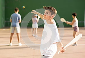 Young man with wooden paleta playing pelota goma on outdoor court photo