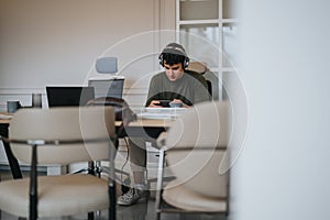 Focused young man studying with headphones at a spacious modern table